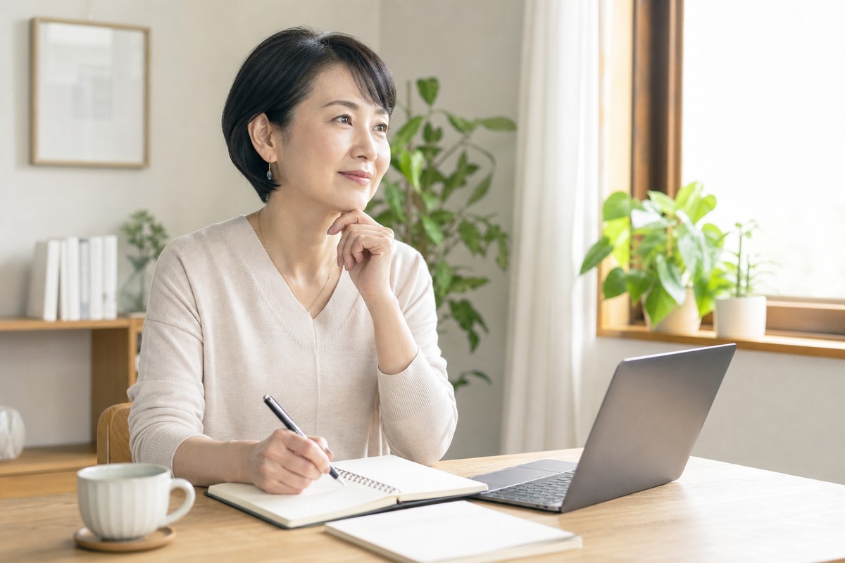 自宅でノートに今後のキャリアプランを書き出す50代女性