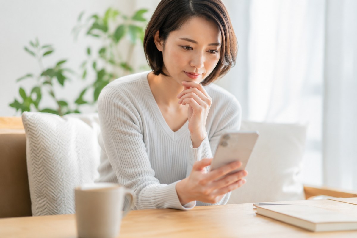 スマートフォンでマナビーの評判・口コミを調べる女性