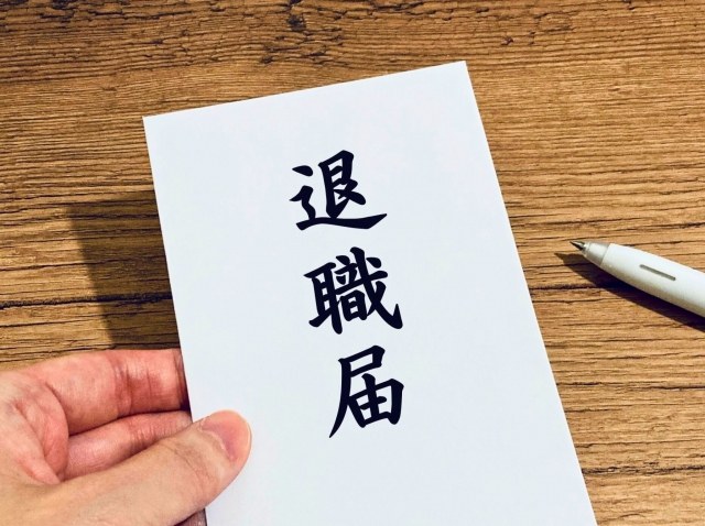 「退職届」と書かれた用紙を手に持つ様子。退職を申し出る場面を表現した写真。