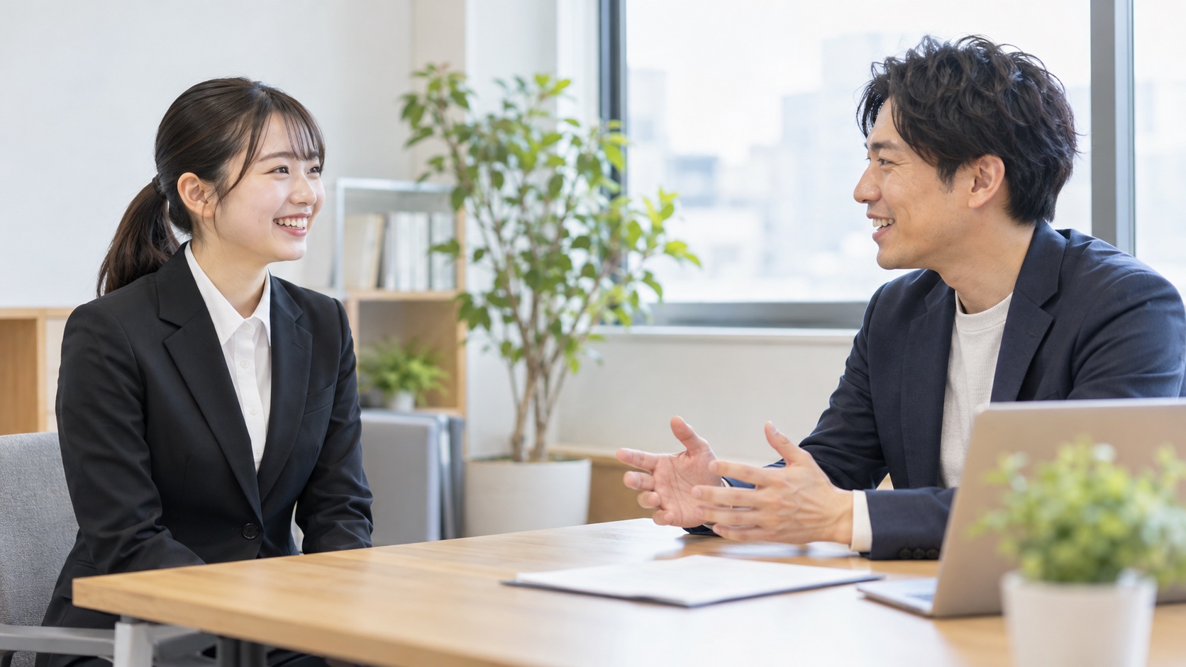 小さな明るいオフィスで社員と話す日本人の就活生